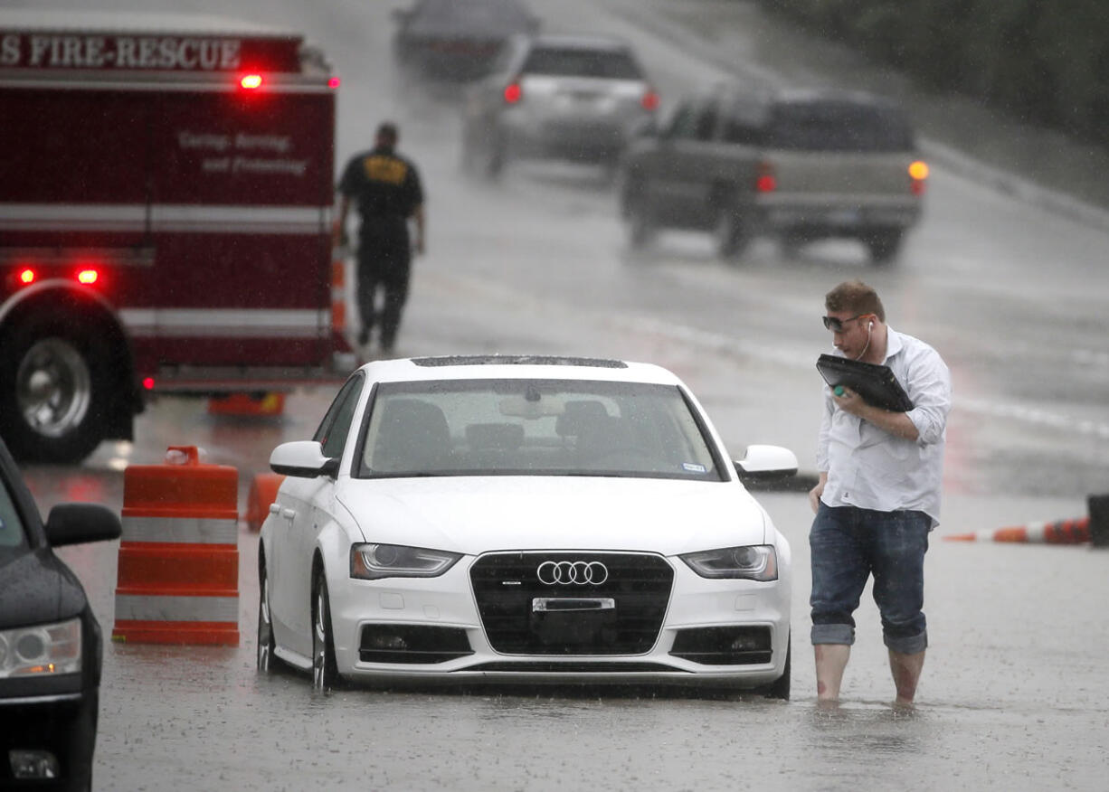 A driver abandons his vehicle after Dallas Fire Rescue arrives to close off a section of  road after it flooded during heavy rain Friday in Dallas.