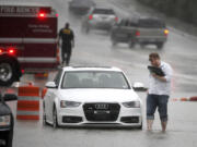 A driver abandons his vehicle after Dallas Fire Rescue arrives to close off a section of  road after it flooded during heavy rain Friday in Dallas.
