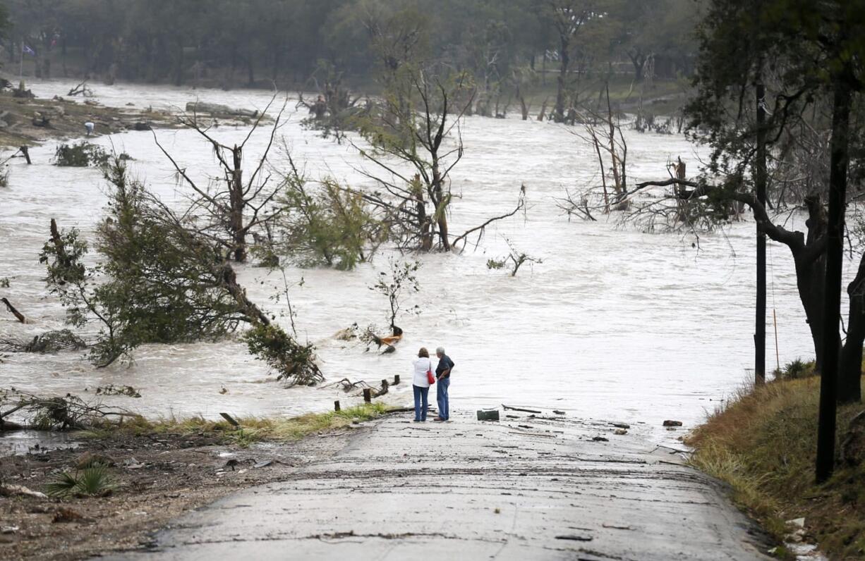 Jim Richardson and his wife, Jeannette, watch the Blanco River recede Friday after a flash flood in Wimberley, Texas.