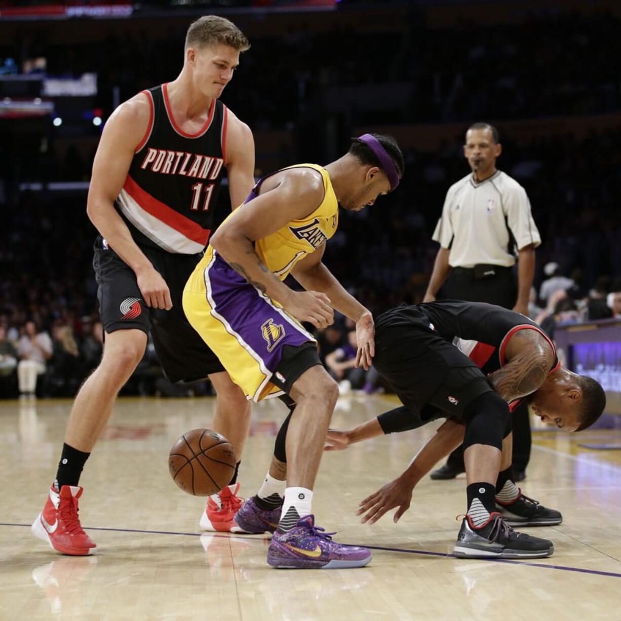 Portland Trail Blazers' Damian Lillard, right, loses the ball under pressure by Los Angeles Lakers' D'Angelo Russell, center, as Trail Blazers' Meyers Leonard watches during the first half of an NBA preseason basketball game Monday, Oct. 19, 2015, in Los Angeles. (AP Photo/Jae C.