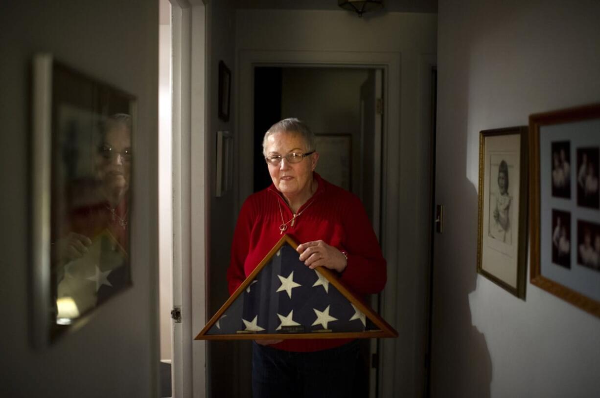 Barbara Belton holds a flag Tuesday memorializing her father-in-law Delbert &quot;Shorty&quot; Belton at her home in Spokane. On Wednesday, a teenage suspect pleaded guilty in the 2013 beating death of the 88-year-old veteran.