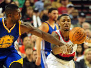 Portland Trail Blazers guard Damian Lillard (0) is fouled by Golden State Warriors center Festus Ezeli (31) as he passes the ball during the second half of a preseason NBA game in Portland on Thursday, Oct. 8, 2015.