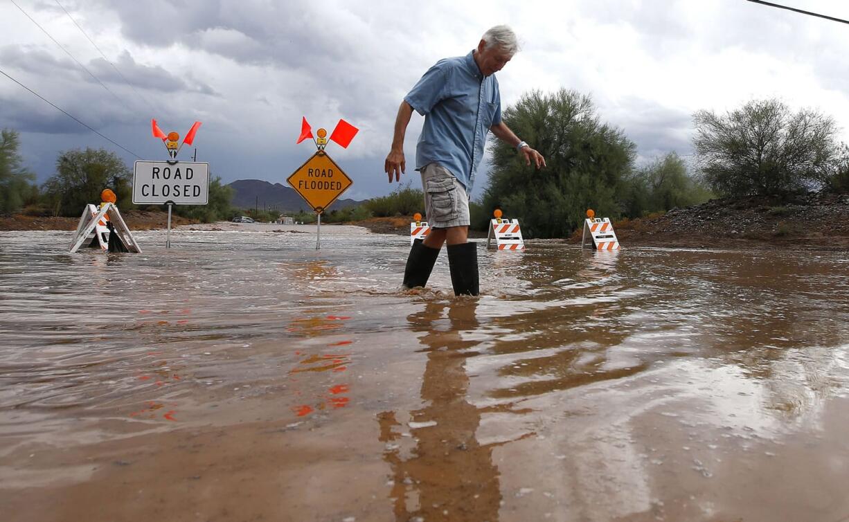 Paul Buff walks through floodwaters on his street Tuesday as severe storms move through Desert Hills, Ariz., just north of the Phoenix metro area. (ROSS D.