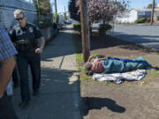 Commander Amy Foster, left, joins elected officials and others on Sept. 21 as they tour an area of downtown Vancouver facing issues with homelessness as a man sleeps on the ground nearby.