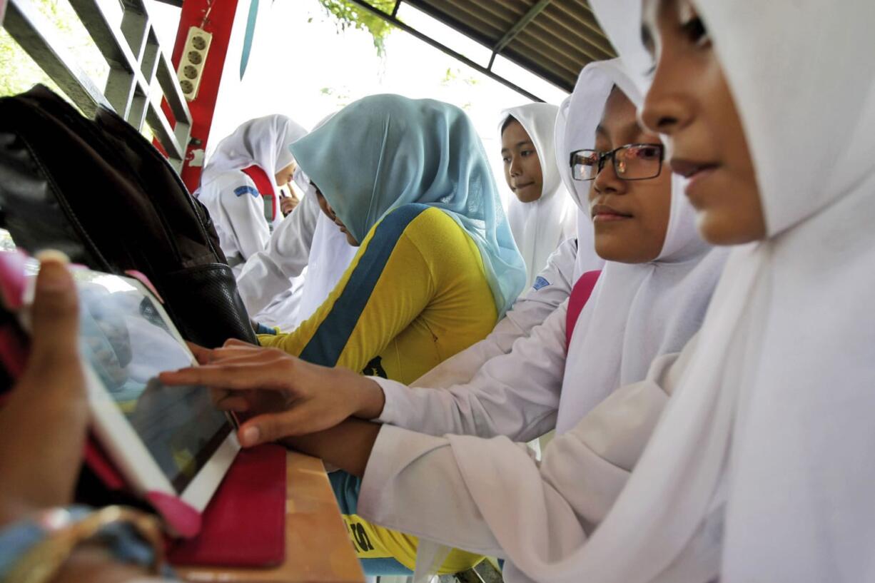 Indonesian students share a tablet computer to check their Facebook accounts at a hot spot in Banda Aceh, Indonesia.