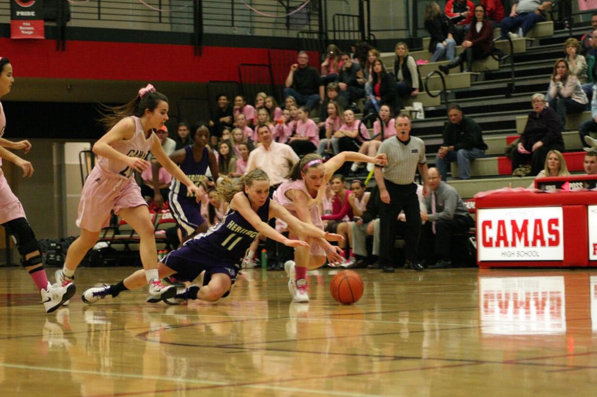 Meghan Finley (right) lunges for the basketball Friday, at Camas High School. The Papermakers beat the Heritage Timberwolves 62-20.