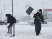 Vincente Echeverria, left, and Glen Harrison clear the driveway leading to the Salvation Army store on Highway 99 in Vancouver on Saturday.