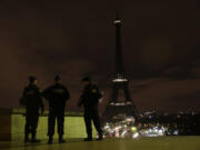 Armed police stand guard Saturday overlooking the Eiffel Tower, which was kept dark in honor of those who died in the terrorist attacks in Paris on Friday.