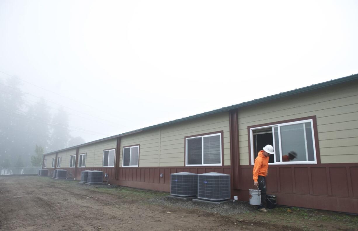 Kenny Hall grabs a bucket of paint as he puts the finishing touches on a modular unit at Daybreak Middle School.