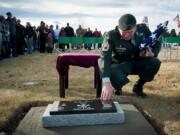 Retired Sgt. 1st Class Matthew Bessler touches the grave marker of Mike, a 9-year-old Belgian malinois, at the end of a memorial service in Powell, Wyo.