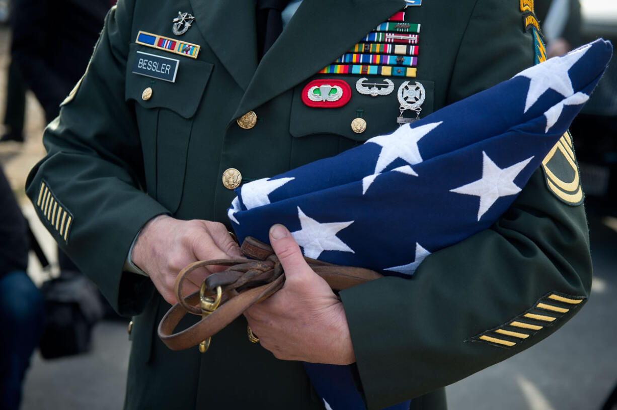 Bessler, a retired U.S. Special Forces K-9 handler, holds Major Mike&#039;s leash and the flag presented to him at a memorial service in honor of his fallen war buddy, a 9-year-old Belgian malinois, in Powell, Wyo.