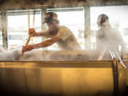 Employees at Crux Fermentation stir hops at Crux&#039;s factory in Bend, Ore.