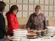 Volunteers Lora Rollins (center) and her daughter, Isabella, 12, talk to Al Schmid, who leads the annual coordination of the Knights of Columbus Thanksgiving dinner preparation and delivery. Schmid, 75, has been participating in the effort for 29 years. &quot;He is very humble,&quot; Lora Rollins said of Schmid. &quot;He does so much. He is always there to lend a hand if you need it.