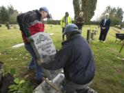 Joey Fuerstenberg, left, and Kyle Cochran of Vancouver Granite Works replace a grave marker for Alexander Stuber at the Camas Cemetery.