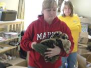 Shannon Collins of Wisconsin carries an armloads of stocking hats for gift boxes headed for her late son's unit in Afghanistan on Sunday.