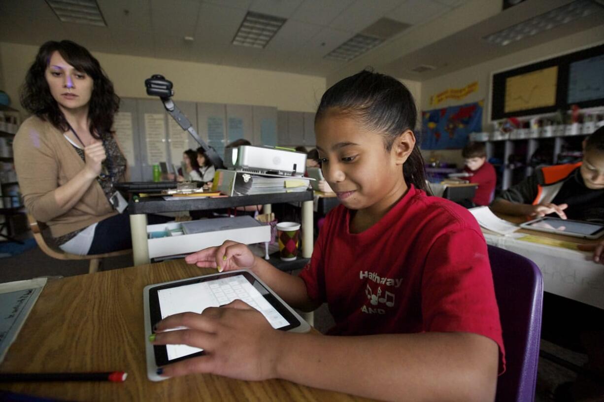 Fifth-grader Lilly Finucane, 10, a student in the class of Erin Hayes, left, at Hathaway Elementary School in Washougal, uses an Apple iPad.