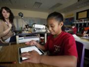 Fifth-grader Lilly Finucane, 10, a student in the class of Erin Hayes, left, at Hathaway Elementary School in Washougal, uses an Apple iPad.