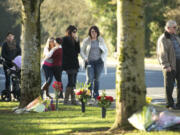 A group of people stop to pay their respects Monday afternoon at the site of a hit-and-run crash that killed two women Sunday night at the intersection of Northeast 72nd Avenue and Northeast Vancouver Mall Drive.