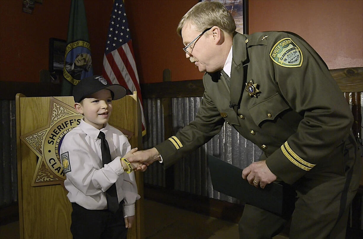 Cole Merle, 6, is congratulated by Clark County Chief Criminal Deputy Mike Evans on Tuesday after being sworn in as an honorary sheriff.