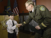 Cole Merle, 6, is congratulated by Clark County Chief Criminal Deputy Mike Evans on Tuesday after being sworn in as an honorary sheriff.