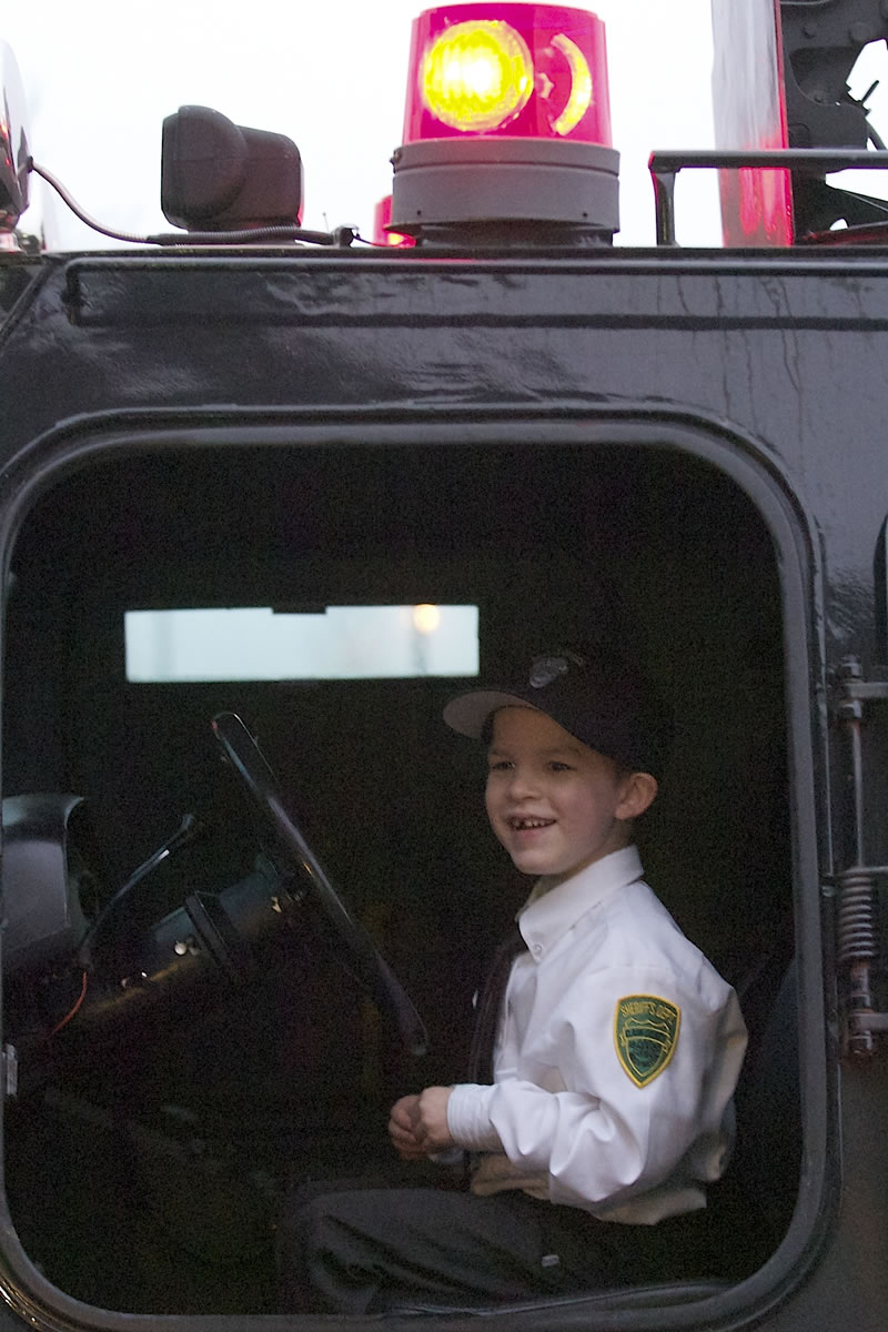 Cole Merle, 6, sits in a Peacekeeper armored police vehicle Tuesday outside the Mill Creek Pub in Battle Ground, where he was sworn in as an honorary sheriff through Clark County's Chief for a Day program. Top: Merle, 6, is congratulated by Clark County Chief Criminal Deputy Mike Evans on Tuesday after being sworn in as an honorary sheriff.