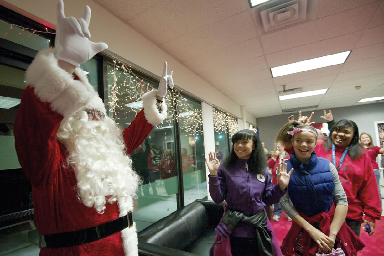 Chris Balduc, left, greets attendees using American Sign Language at a DeafVibe Foundation holiday party on Dec. 13 at their Vancouver office. Balduc is a case worker for the Southwest Washington Center of the Deaf and Hard of Hearing.