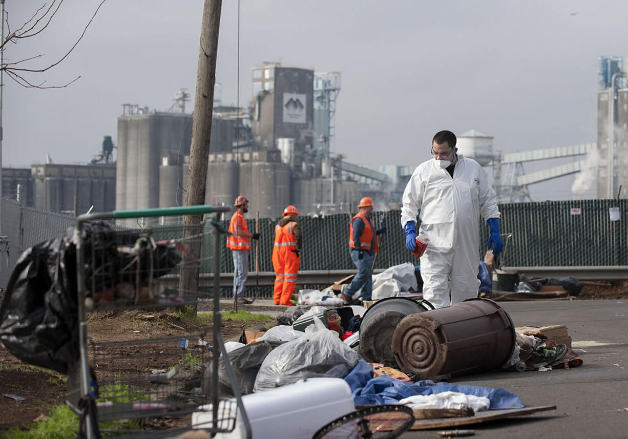 Andrew Newkirk, a mitigation technician of ServiceMaster of Vancouver, searches for biohazards Wednesday morning on West 12th Street, where up to 150 homeless people had been camping.