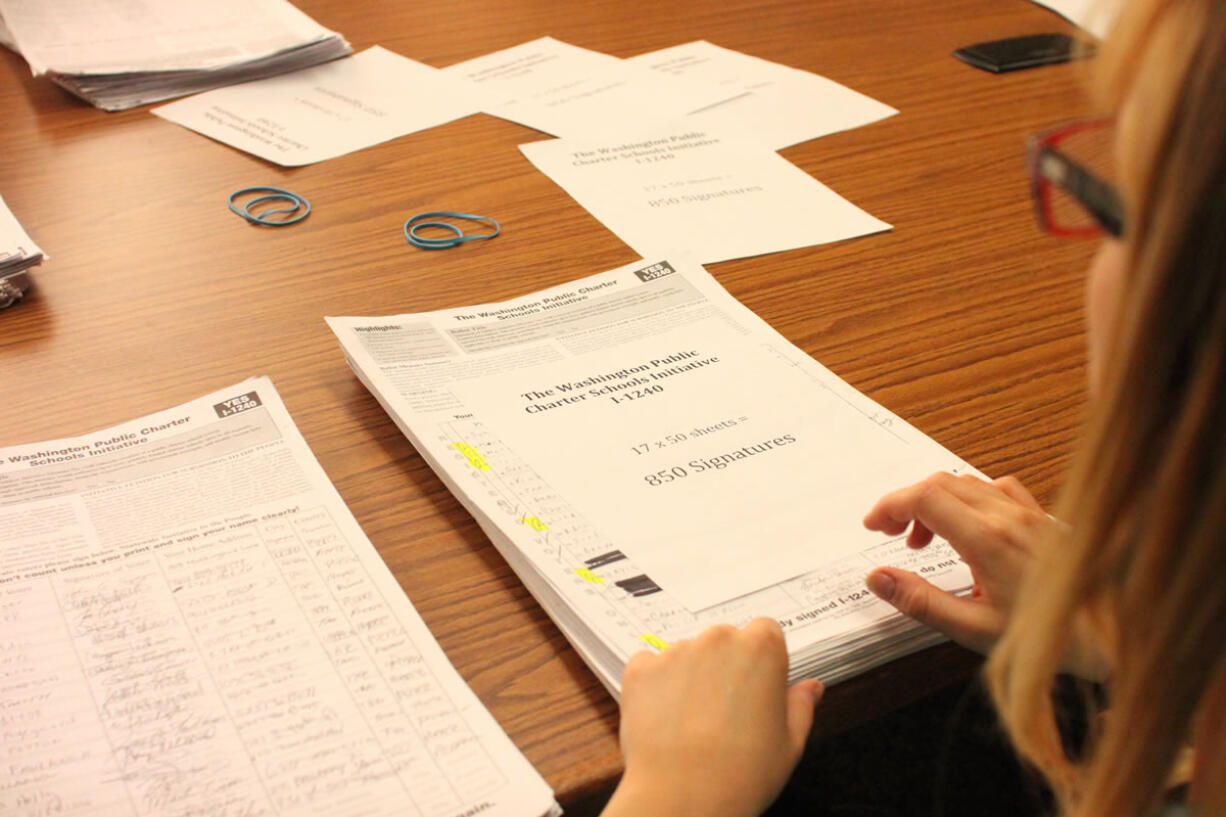 Renee Wyman, a paid signature checker for the state elections office, counts signatures for the charter school Initiative 1240 in July 2012 in the State Elections Office in Olympia.