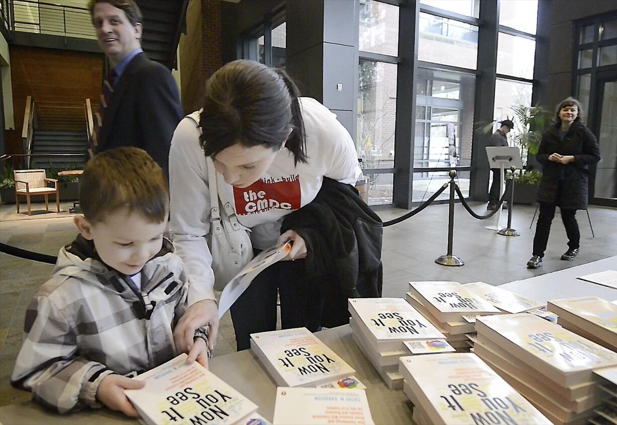 Melissa Carroll, a digital technology student at Washington State University Vancouver, and her son, Liam Carroll, 4, pick up a book at the 2014 launch of the #nextchapter program at Vancouver City Hall.