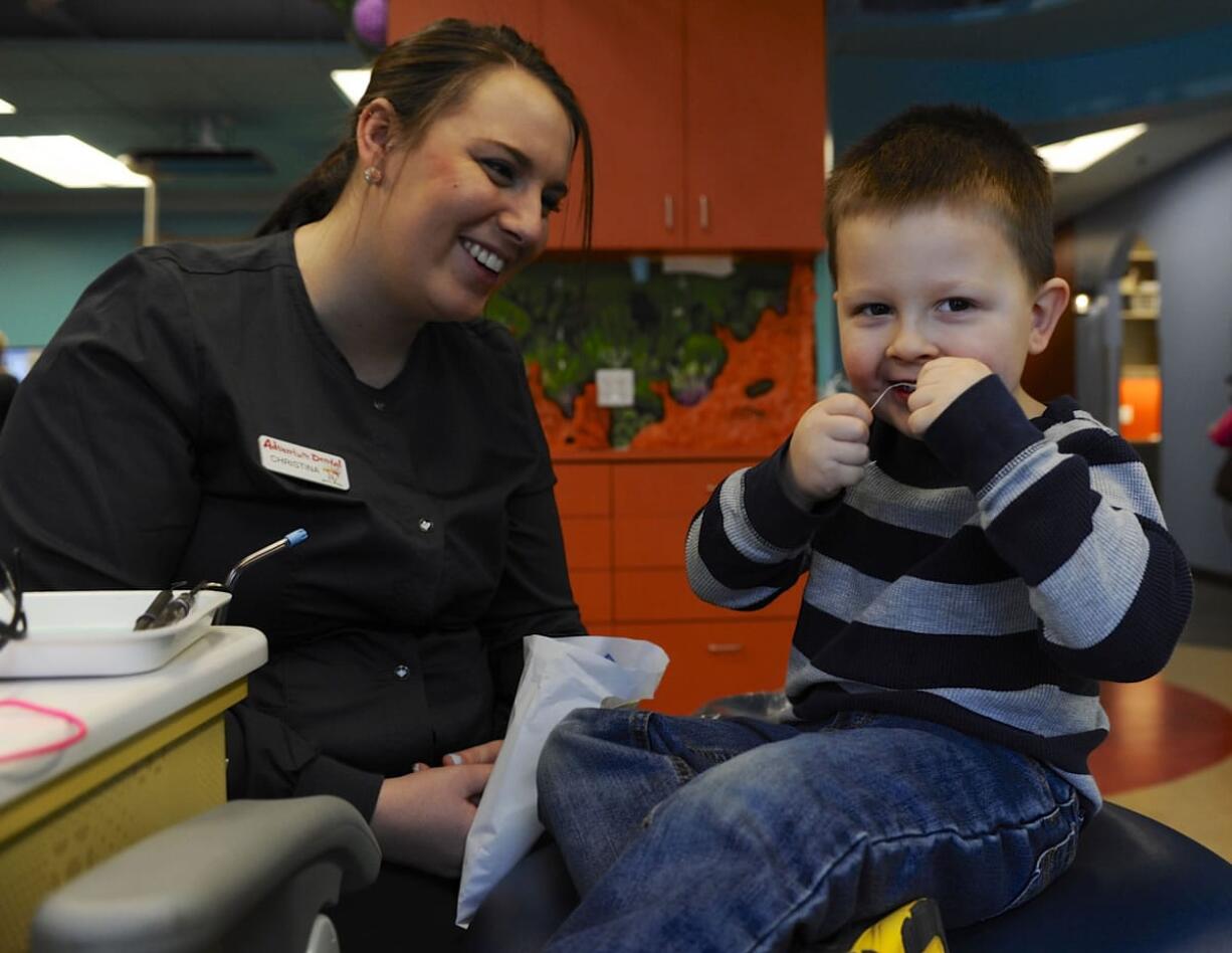 Austin Labrum demonstrates his flossing technique for Christina Beard during a dental visit Thursday at Adventure Dental in Vancouver.