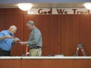 County facilities managers Darrel Stump, left and Mike Wright put glue on the back of a letter as the &quot;In God We Trust &quot; slogan is installed Thursday.