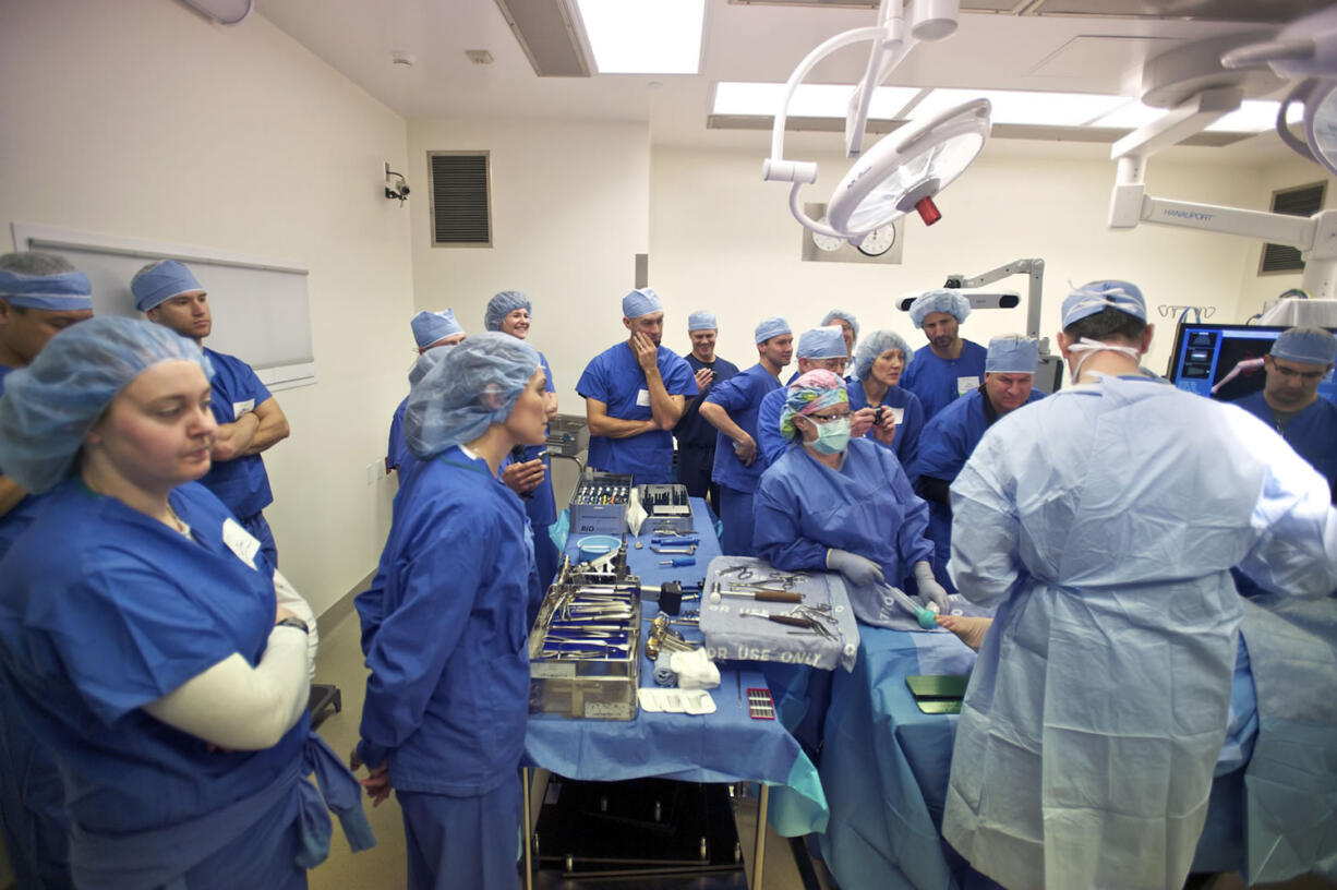 Physical therapists watch Dr. Todd Borus perform a partial knee replacement on a cadaver leg Saturday at Legacy Salmon Creek Medical Center.