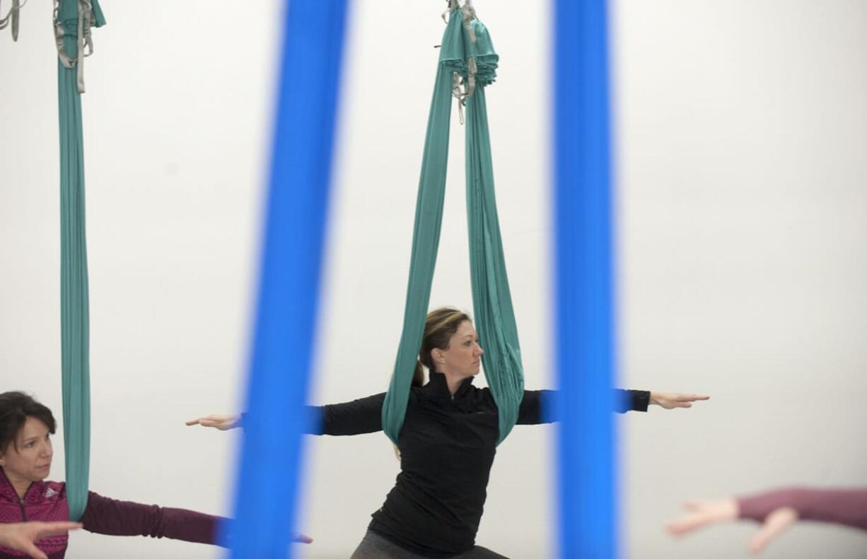 Crystal Hoss stretches with the aid of a silk hammock during an aerial yoga class Wednesday at Virtuosity Performing Arts Studio in downtown Camas.