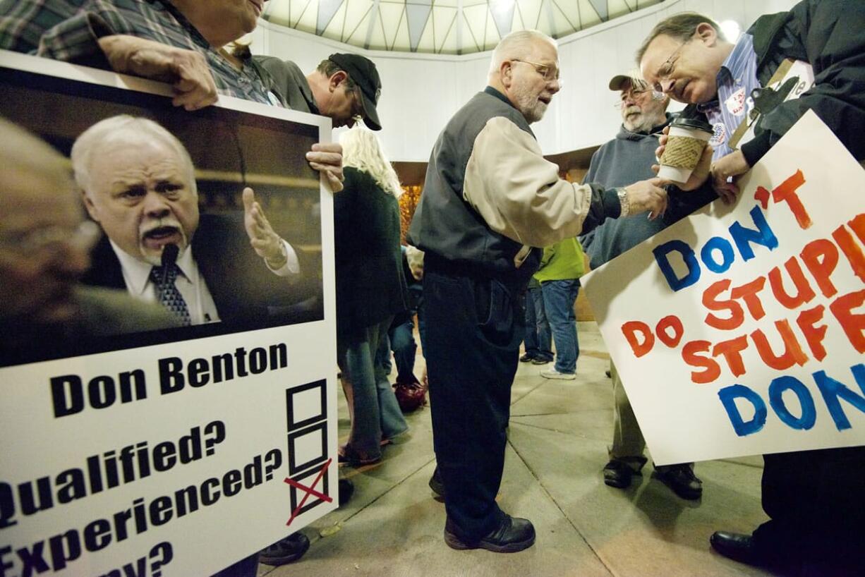 Ed Barnes, center, checks the time with Ron Goodman, right, before the start of a Tuesday night meeting of the Clark County commissioners. Barnes and a large group of supporters gathered in front of the county's Public Service Center before the meeting, many with signs decrying the Republican majority on the board of commissioners for their decision to hire state Sen. Don Benton, R-Vancouver.