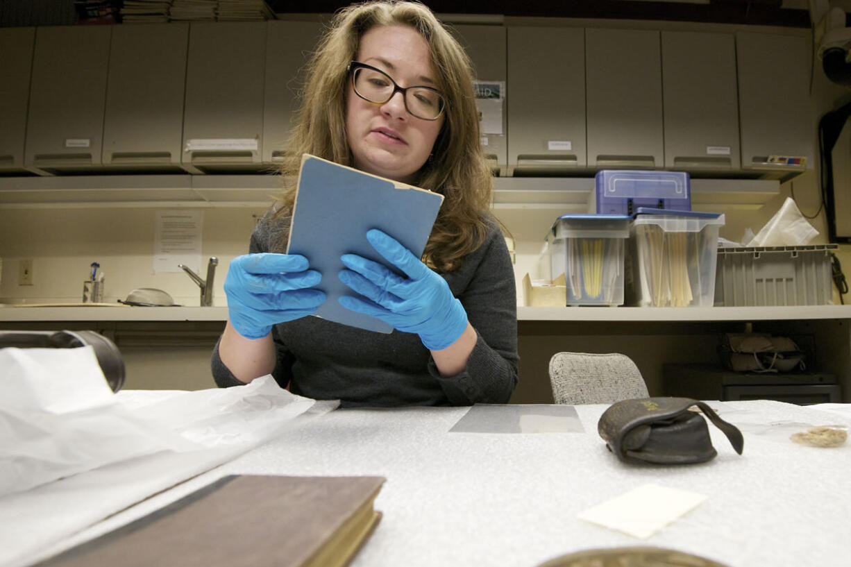 Museum technician Meagan Huff, a museum tech at the Fort Vancouver National Historic Site, examines an 1862 booklet about firing and maintaining a rifle musket.