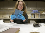 Museum technician Meagan Huff, a museum tech at the Fort Vancouver National Historic Site, examines an 1862 booklet about firing and maintaining a rifle musket.