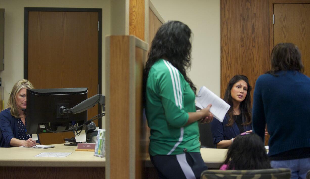 Clark Public Utilities customer service representative Esther Koski, seated at right, helps a family at the Clark Public Utilities Service Center in Orchards, The utility staffs its customer service operations 24 hours a day, seven days a week.