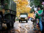 Leona Klicke, 3, waves Saturday as vehicles from the Military Vehicles Collectors Club of Oregon pass by during the 29th annual Veterans Day Parade at Fort Vancouver. (Photos by Molly J.