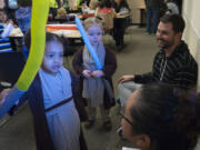 Two-year-olds Chloe Sophia Brent, front left, and Helena Boudreaux, dressed as Jedi knights, play with their light sabers during the &quot;Star Wars&quot; extravaganza at the Camas Public Library on Saturday. Helena&#039;s father, Mathew, back right, is a big &quot;Star Wars&quot; fan and made the costumes for the girls.