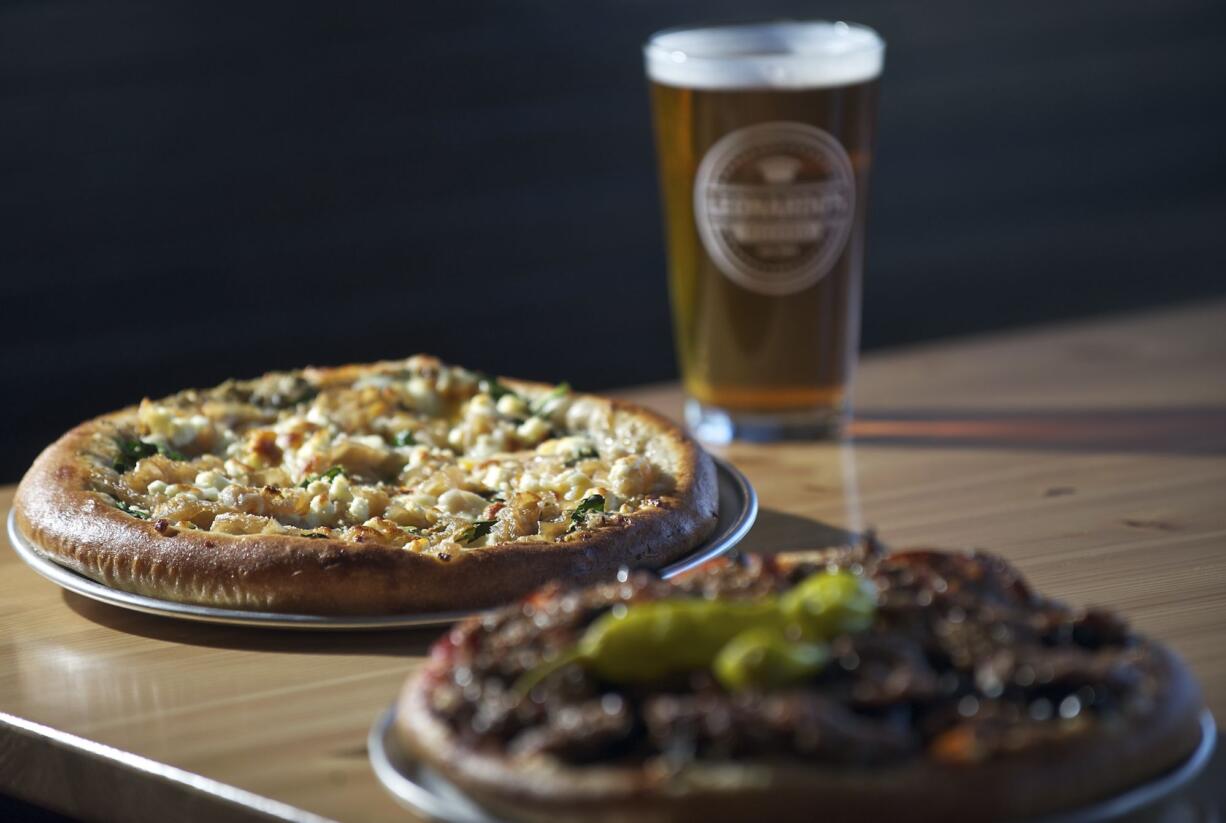 The Little Oven Annie pizza, background, and the Leonardo's supreme pizza are complemented by one of 17 beers on tap at Leonardo's Pizzeria in Vancouver.