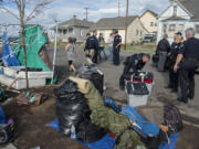 Cpl. Duane Boynton, with white gloves, labels a container as he lends a hand to a woman, left in stripes, while she prepares to move from her campsite in downtown Vancouver on Monday morning, Nov. 2, 2015.