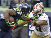 Seattle Seahawks running back Thomas Rawls, left, pushes off San Francisco 49ers inside linebacker Michael Wilhoite, right, as he runs for a touchdown during the second half of an NFL football game, Sunday, Nov. 22, 2015, in Seattle.