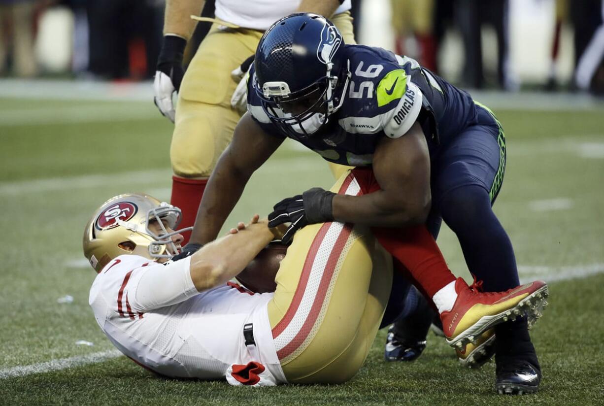 Seattle Seahawks defensive end Cliff Avril, right, sacks San Francisco 49ers quarterback Blaine Gabbert, left, in the second half of an NFL football game, Sunday, Nov. 22, 2015, in Seattle.