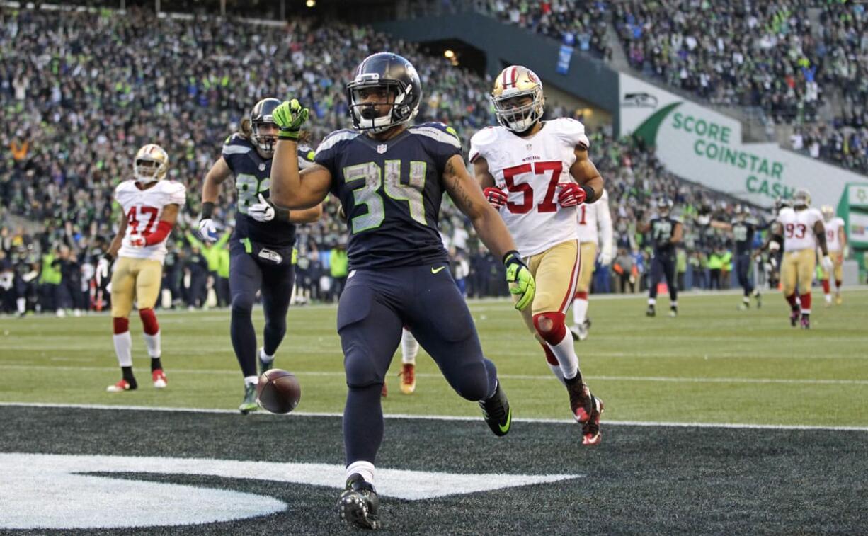 Seattle Seahawks running back Thomas Rawls (34) drops the ball after scoring a touchdown ahead of San Francisco 49ers inside linebacker Michael Wilhoite (57) during the second half of an NFL football game Sunday, Nov. 22, 2015, in Seattle.