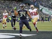 Seattle Seahawks running back Thomas Rawls (34) drops the ball after scoring a touchdown ahead of San Francisco 49ers inside linebacker Michael Wilhoite (57) during the second half of an NFL football game Sunday, Nov. 22, 2015, in Seattle.