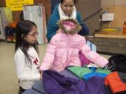 Vancouver Police Department Officer Benny Romiti helps Leonardo Gomez, 9, try on a new coat Monday evening at Washington Elementary School in Vancouver. The Vancouver Police Activities League, along with McCord&#039;s Vancouver Toyota-Scion, organized the coat drive.