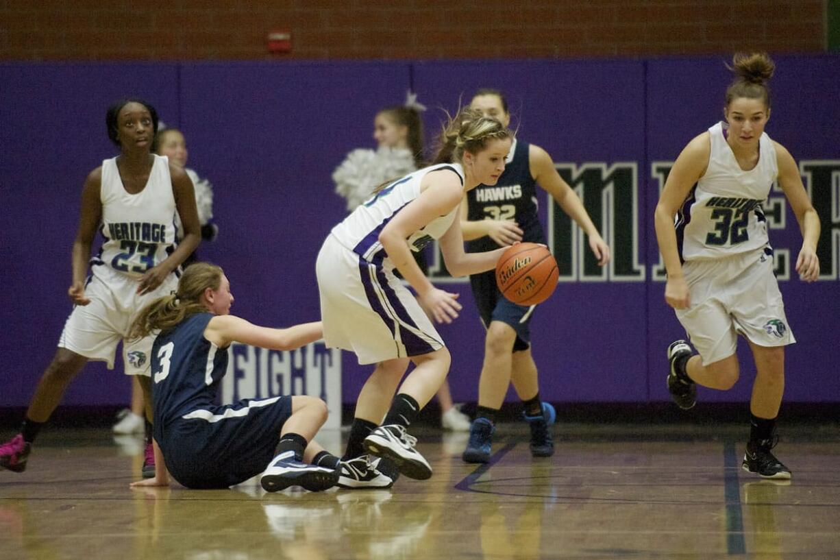 After breaking up a play against Hockinson, Ashley Edwards, (4), center, of Heritage High School, takes the basketball down court on a fast break with senior teammates Mesha Branch, (23), left, and Madison Bare (32), right.