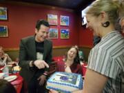 Seth Aaron Henderson laughs at a photograph of himself on a cake presented to him by Karen McMillen and Cliff McMillen, right, owners of Vancouver Pizza, at the restaurant Thursday.