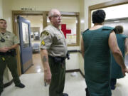 Corrections Sgt. Jack Huff, center, escorts inmates wearing suicide smocks to an elevator as they make their way to court from the Clark County Jail.