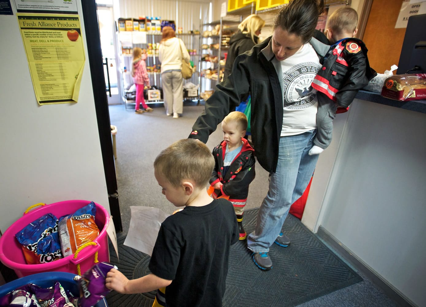 Battle Ground newcomer Stacy Pfeifer, 32, steers her children -- from left, Benjamin, 4, Caeden, 2, and Dalin, 1 -- through the North County Community Food Bank. Pfeifer said she and her husband are both disabled military veterans; on Nov.